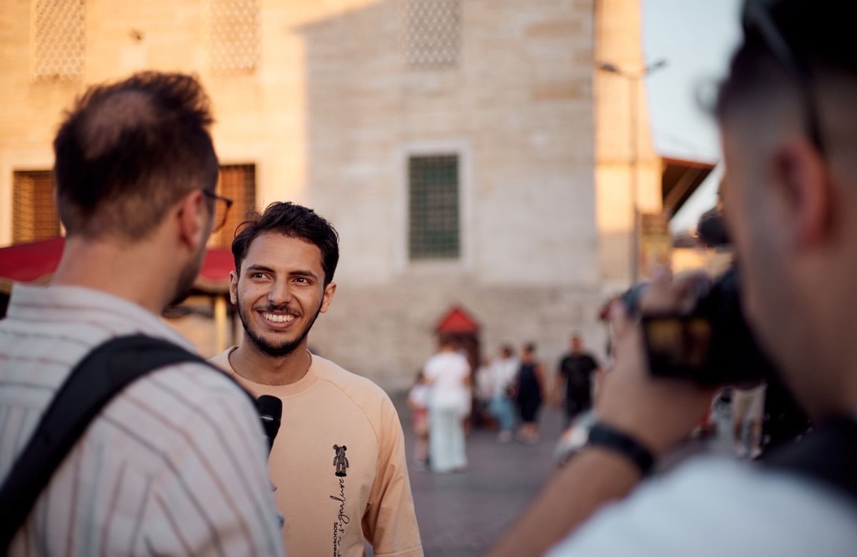 Interview filmée en extérieur, la caméra au premier plan